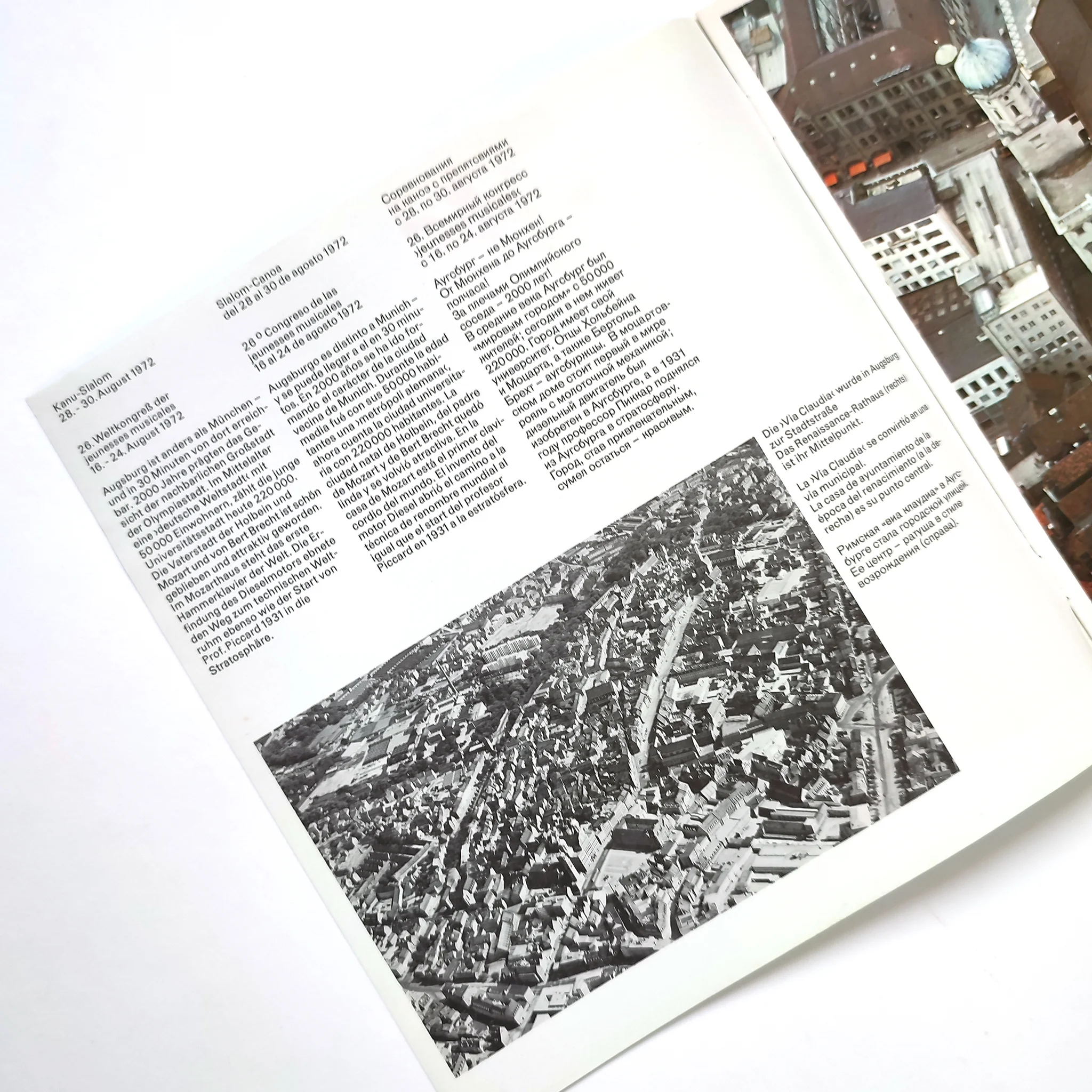 Open brochure with a black-and-white aerial city photo and text in multiple languages. The mood is informative and historical.