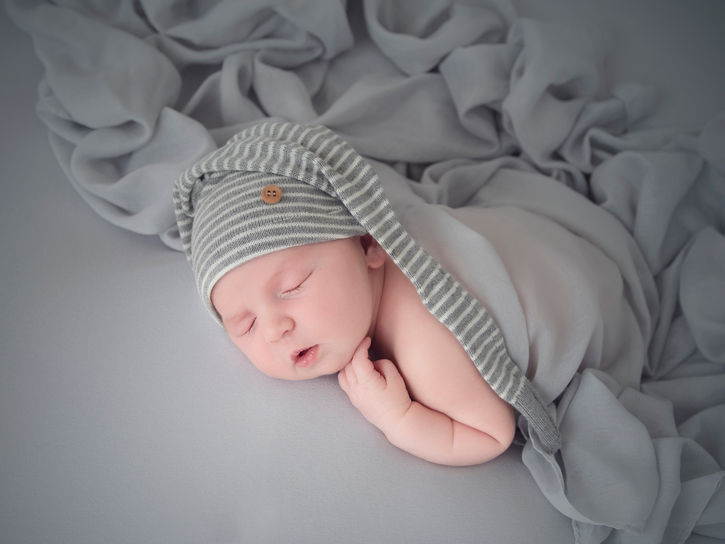 baby boy wearing a long hat sleeping peacefully during his newborn photoshoot