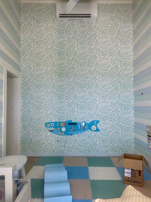 Nursery wall with sea-themed wallpaper and whale mural