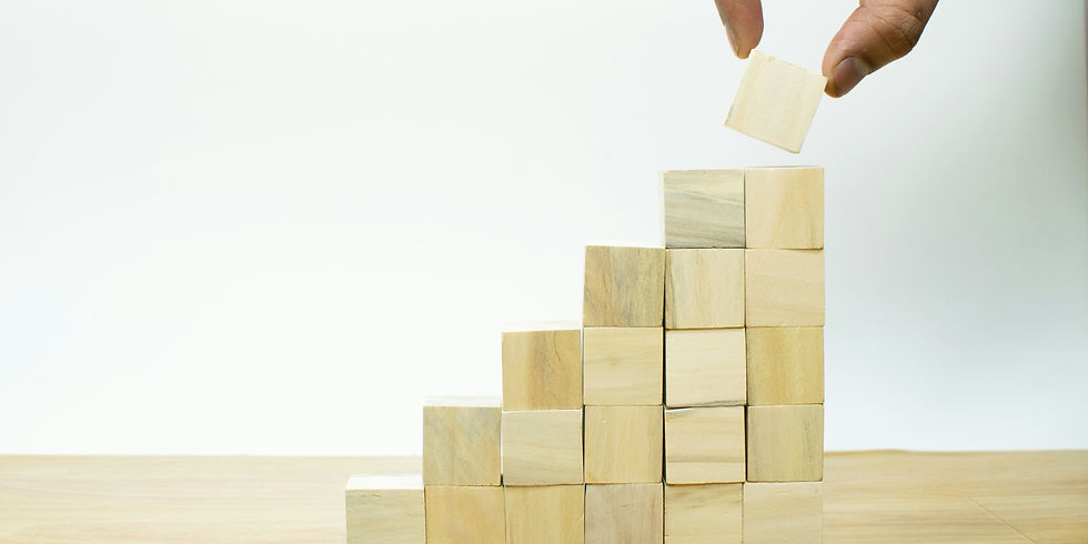 building blocks being stacked with someone placing the top one on the top, they are build like stairs leading up
