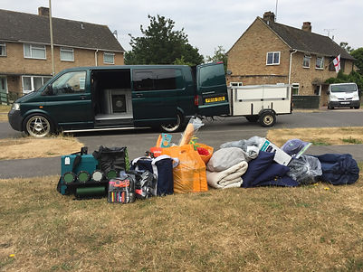 Campervan with camping gear laid out on the lawn in front of it