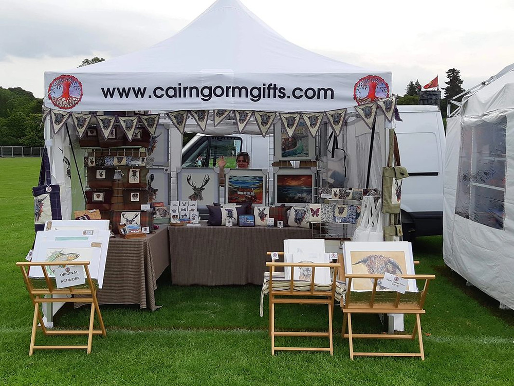 Photograph of a market stall with cards, paintings and bunting