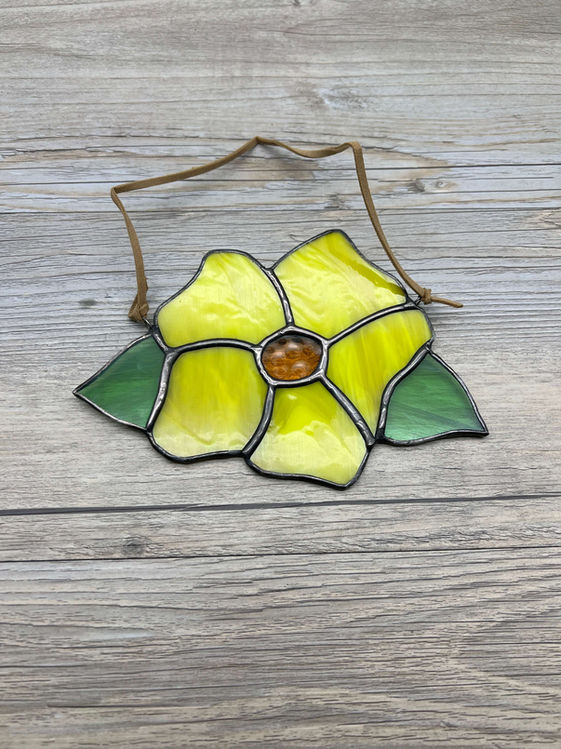 Handcrafted stained glass yellow flower with brown string, spring decor background.