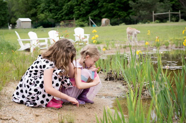 2 little girls kneeling at a pond