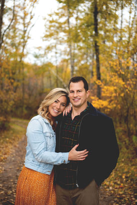 engaged couple holding each other with fall leaves all around