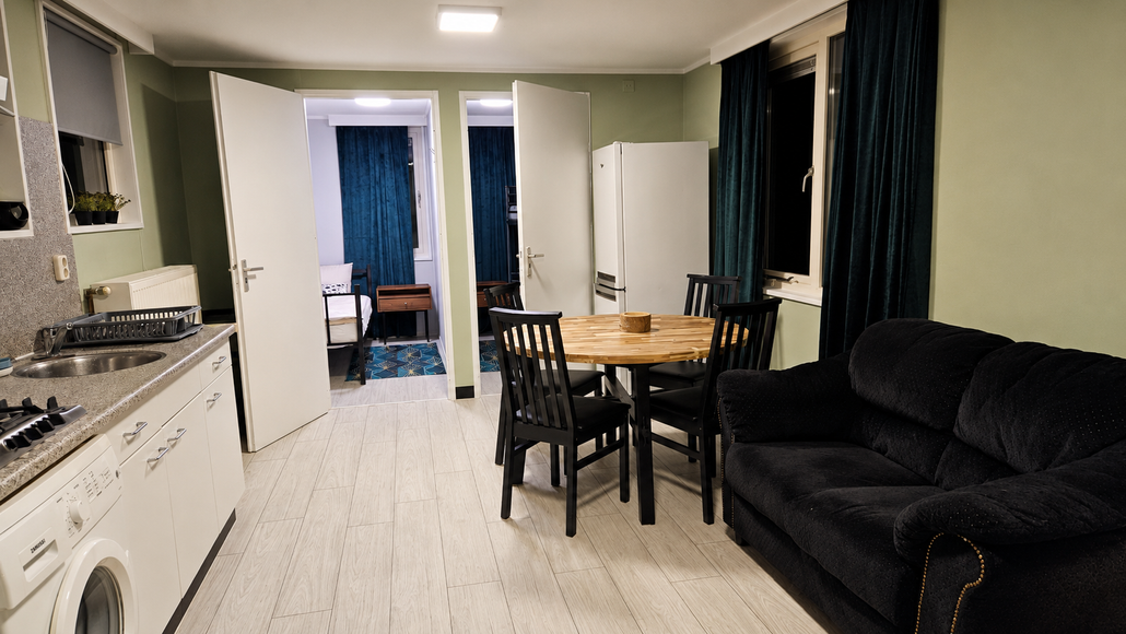 Przestronny salon z czarną sofą i okrągłym stołem jadalnianym – domy na wynajem Frankfurt Oder