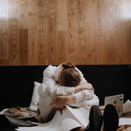 A woman sitting on the floor with her head resting on her knees while papers, a laptop, and coffee cups surround her, representing burnout, overwhelm, ADHD, and trauma.