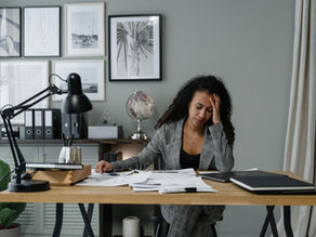 A woman sitting at a desk with her head in her hand.