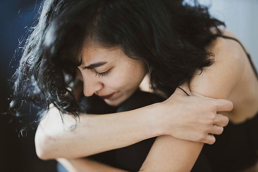 An adult holding herself with a stressed expression.