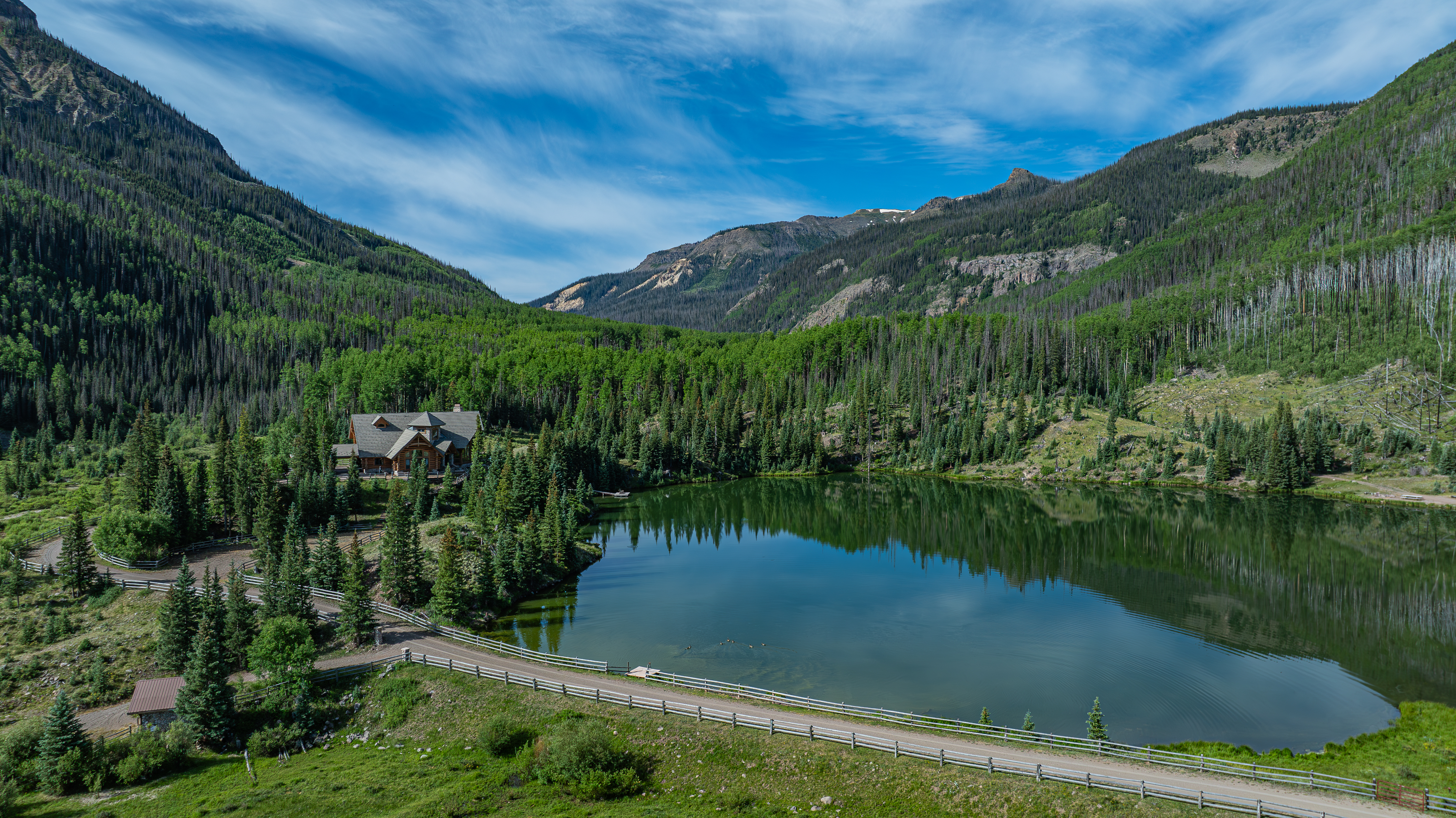 A high mountain lake with a luxury cabin sitting on the edge of the water in Creede, Colorado.