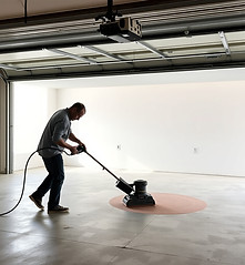 someone sanding down garage floor with a
