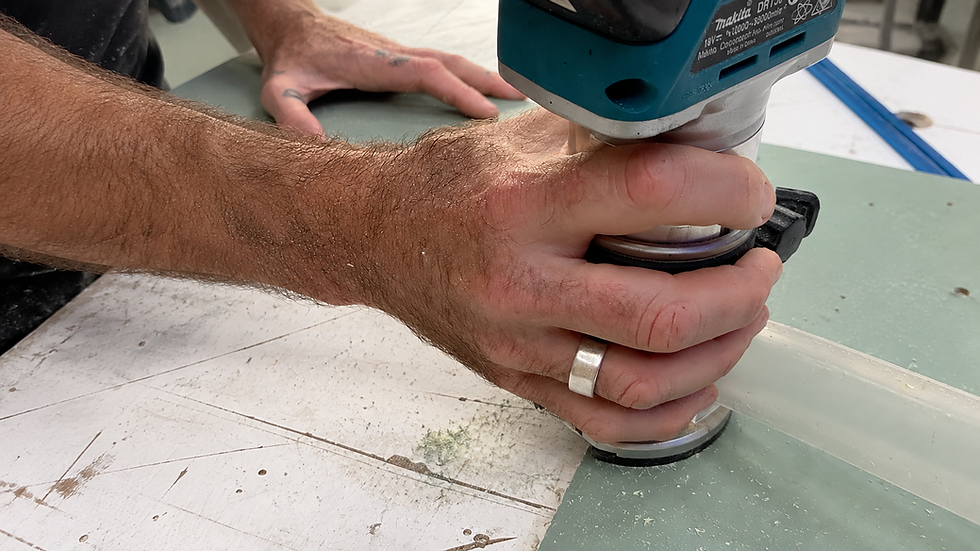 Craftsman using a router to precisely shape a custom camper van component in a workshop.