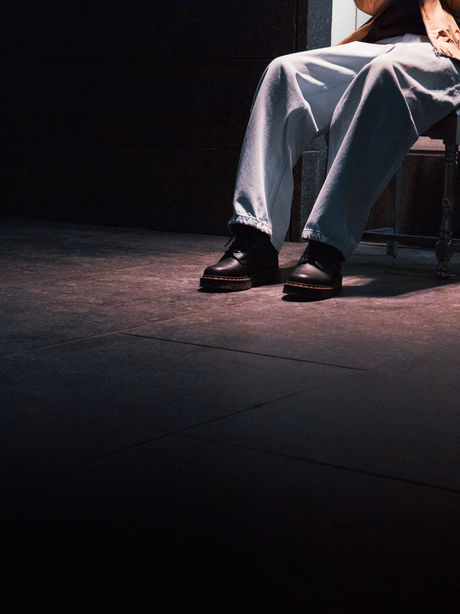 Des pieds surgissent dans l'ombre, une personne assise