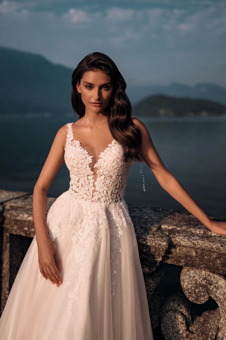 Mariée en robe blanche en dentelle devant le lac