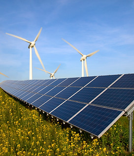 Photovoltaikanlage auf Feld mit Windrädern im Hintergrund – nachhaltige Solarstromerzeugung für Wohn- und Gewerbegebäude.