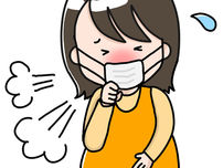 オレンジ色の服を着てマスクをした妊婦さんが咳をしている画像