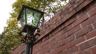 両側に高い木塀が続く、京都の伝統的な細い路地。石畳の道沿いに等間隔で置かれた行灯が奥行きを感じさせる。