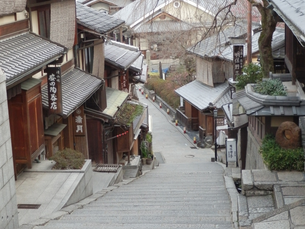 京都の産寧坂（三年坂）を見下ろした風景。急な石畳の階段の両側に、瓦屋根の伝統的な木造建築の店舗や民家が密集して立ち並んでいる。