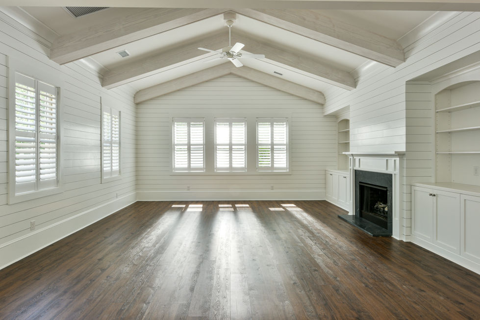 an empty living room with a fireplace and ceiling fan