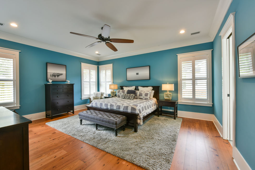 a bedroom with blue walls and a ceiling fan