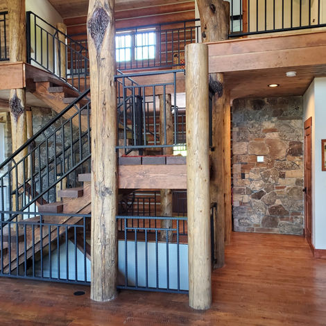 Log home interior with timber columns and staircase