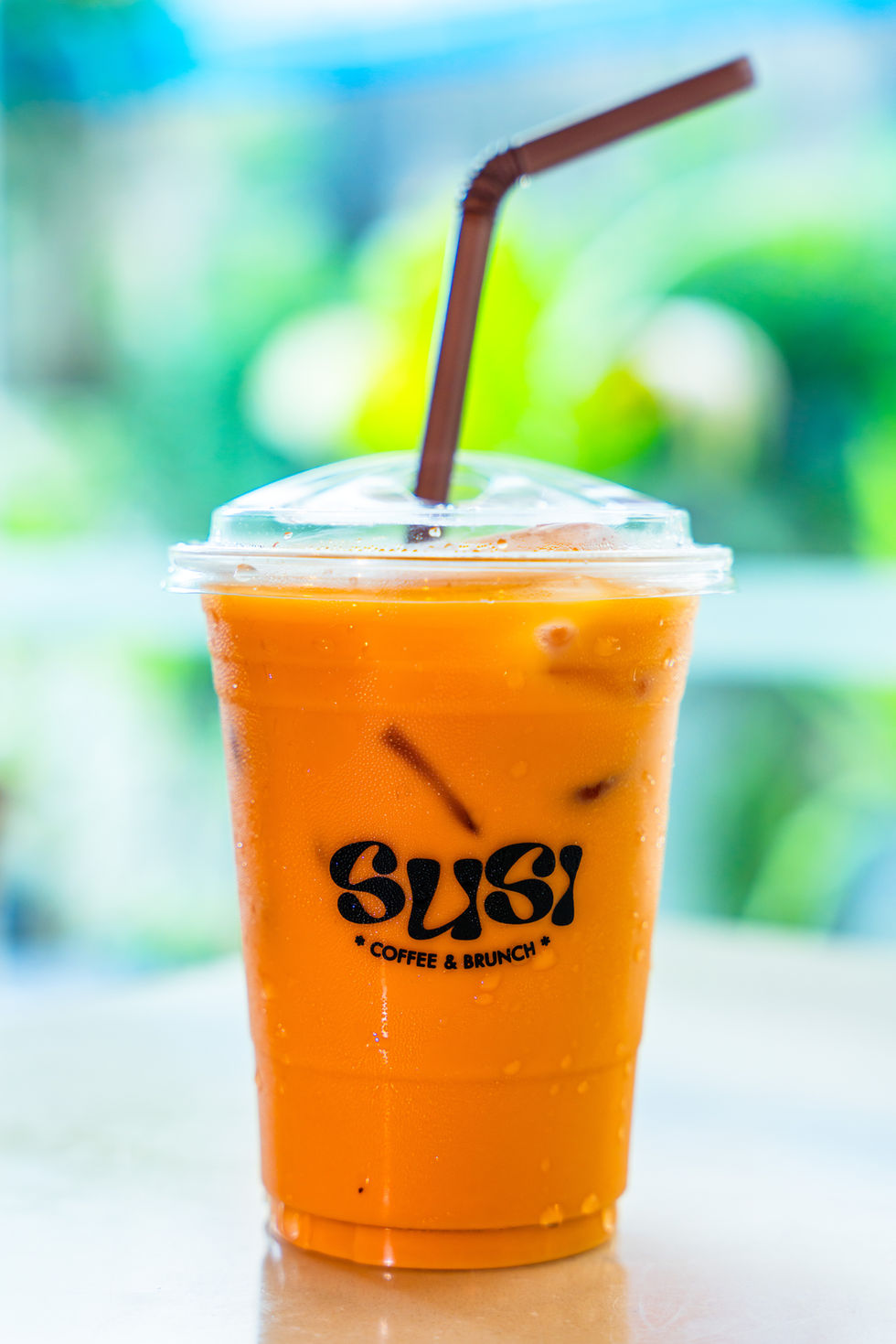 Iced Thai tea in a plastic cup with SUSI COFFEE & BRUNCH logo