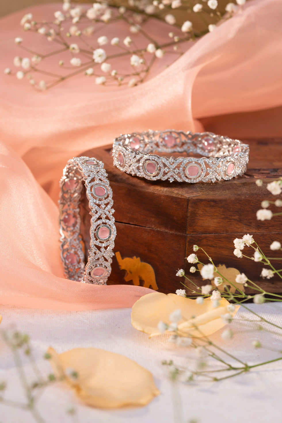 Silver bangles with pink stones on wood
