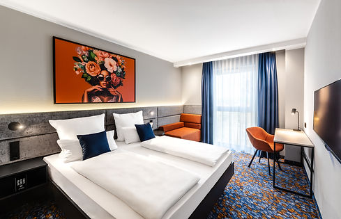 Modernes Hotelzimmer mit Doppelbett und einem Bild über dem Kopfende
