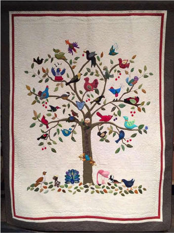 Birds of a Feather quilt made by the Clark County Quilters features a tree and many different kinds of birds.  The background is densely quilted.  