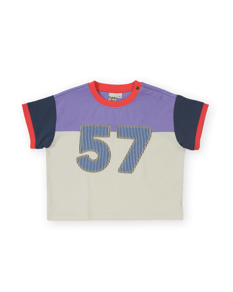Children’s color-block T-shirt with purple top, cream body, navy sleeves, red trim, and large “57” graphic on the front.