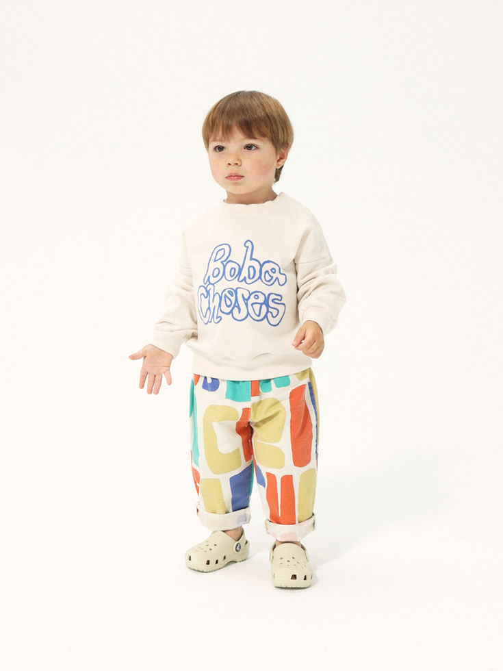 Child standing and wearing the printed shorts with a cream sweatshirt.
