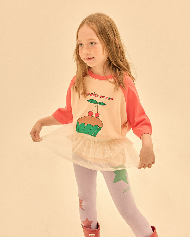 Close-up of a child wearing the raglan T-shirt, showing the cupcake graphic and coral sleeves