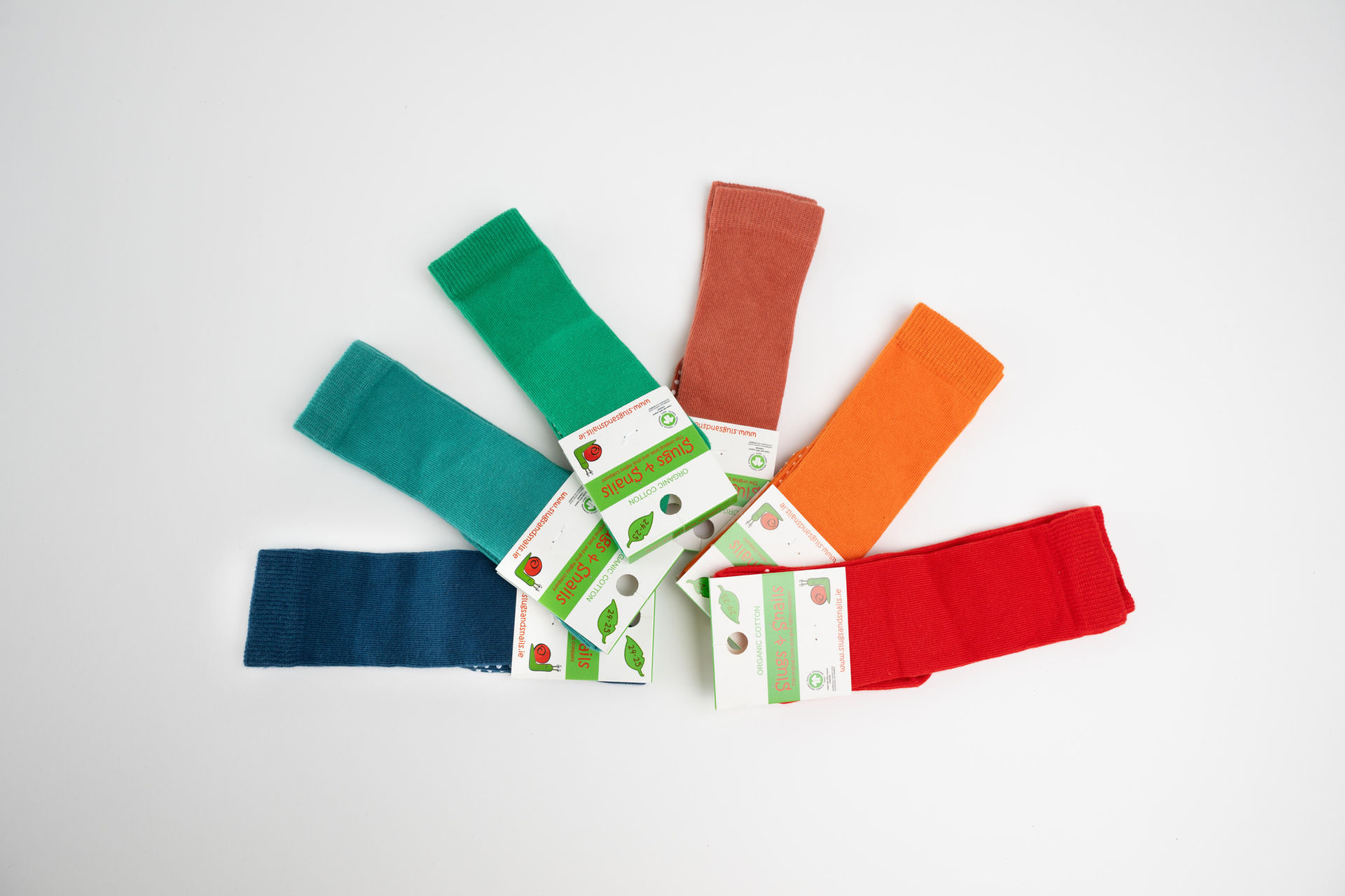 Circular flat lay of Slugs and Snails socks in assorted bright tones, featuring the Sunset Orange pair.