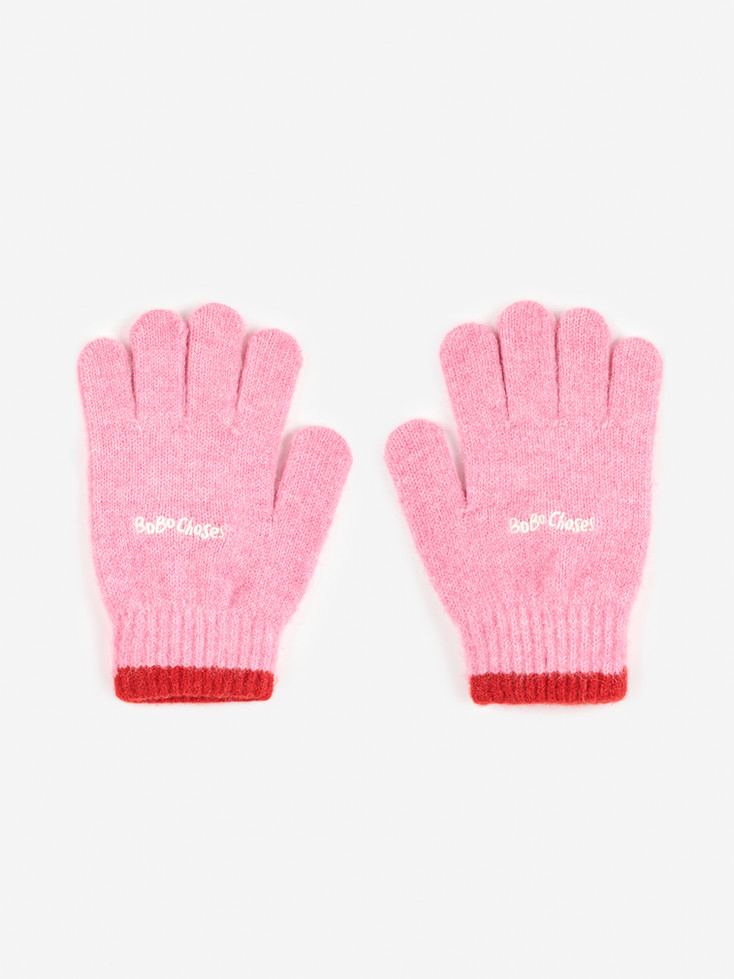 Flat lay of Bobo Choses pink knitted gloves with red cuffs