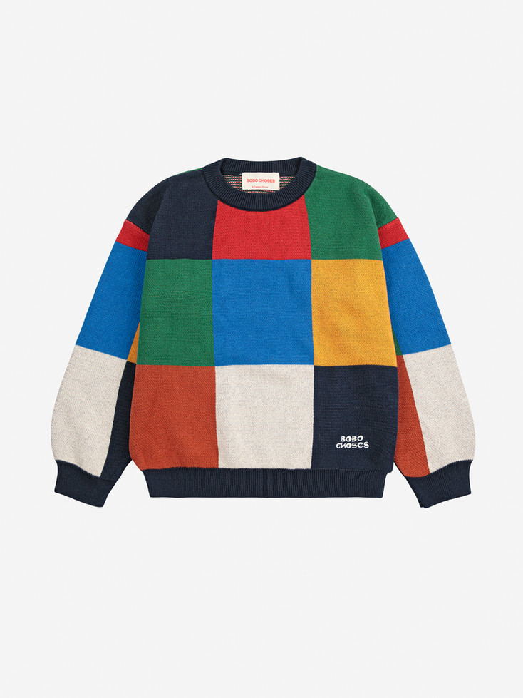 Flat lay of Bobo Choses jumper with bold multicolor tile pattern in red, green, blue, yellow, and off-white blocks