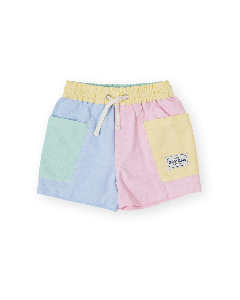 Pastel color-block children’s shorts with blue, pink, yellow, and mint panels and an elastic waistband with drawstring.