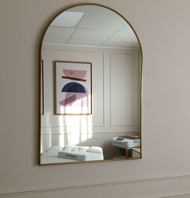 Un miroir dans lequel se reflète une salle de soin élégante avec une table et une machine haut de gamme.