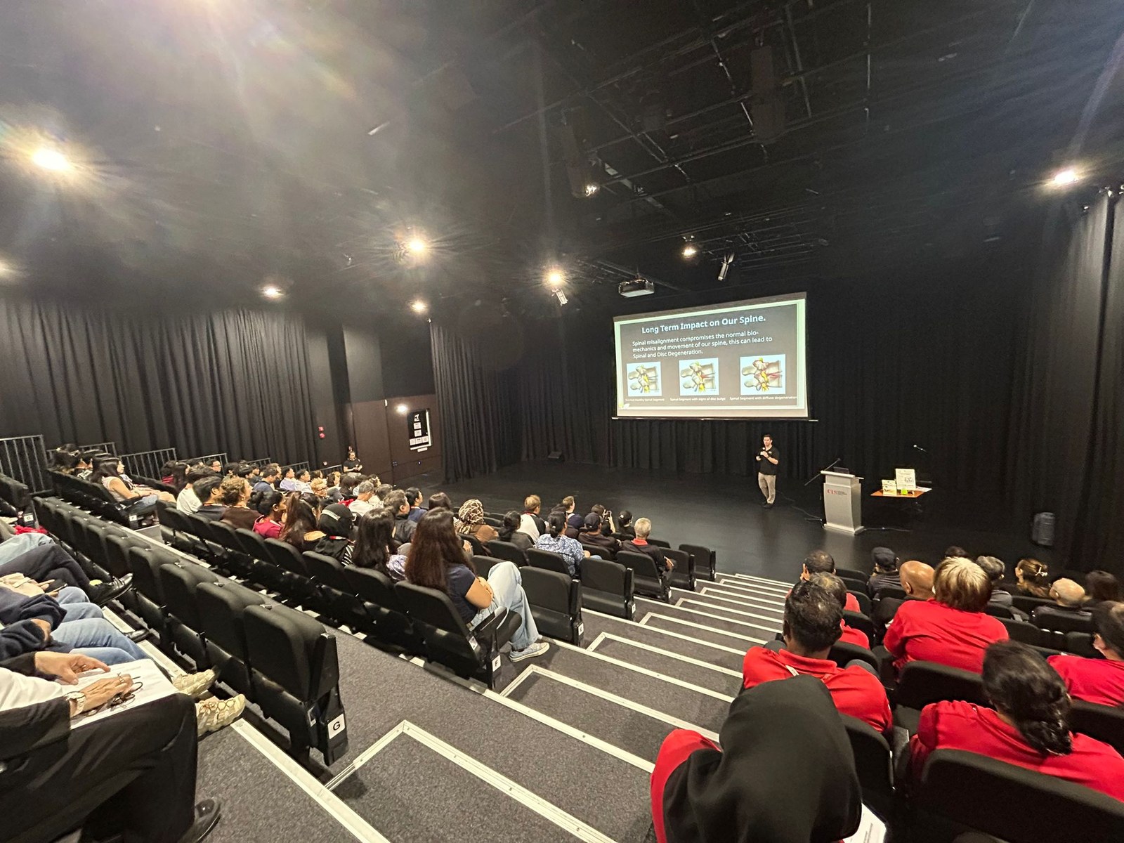 ActiveLife chiropractor presenting on spinal health to a full auditorium