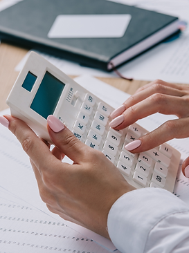 Mão feminina fazendo cálculos em uma calculadora branca