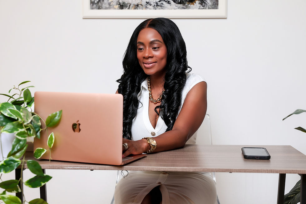 Natalie Wisdom, LCSW, a BIPOC therapist in New York and Connecticut, sits at her desk and smiles while working on her laptop.