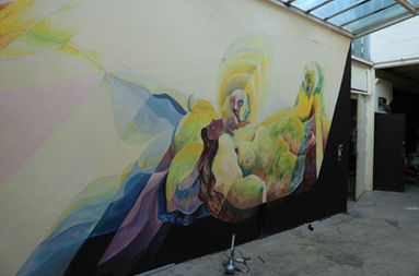 Félix Rouxel. Sous le soleil, gonflent les corps. Acrylique sur parpaing. Octobre 2018. La fresque dans un contexte de soirée. De la lumière tombe de la verrière du plafond. Elle découpe dans le mur de la pièce, un carré de lumière. Autour, Le noir est très dense. Des corps diffractés par la lumière s'apprètent à s'embrasser. Un groupe de femme allongées se fondent à la prairie. Noir Jaune, ocre, vert, bleu, violet.