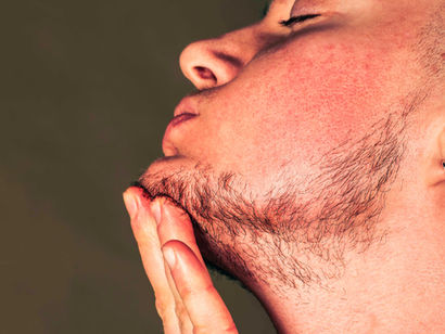 a trans man stroking his beard