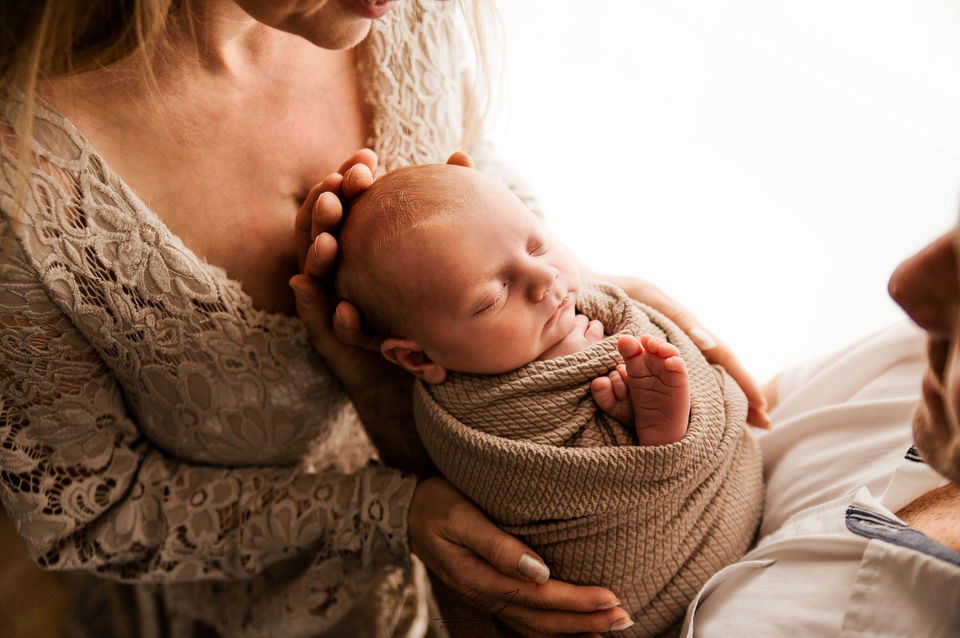 Bébé dans les bras des parents - séance photo nouveau né isère