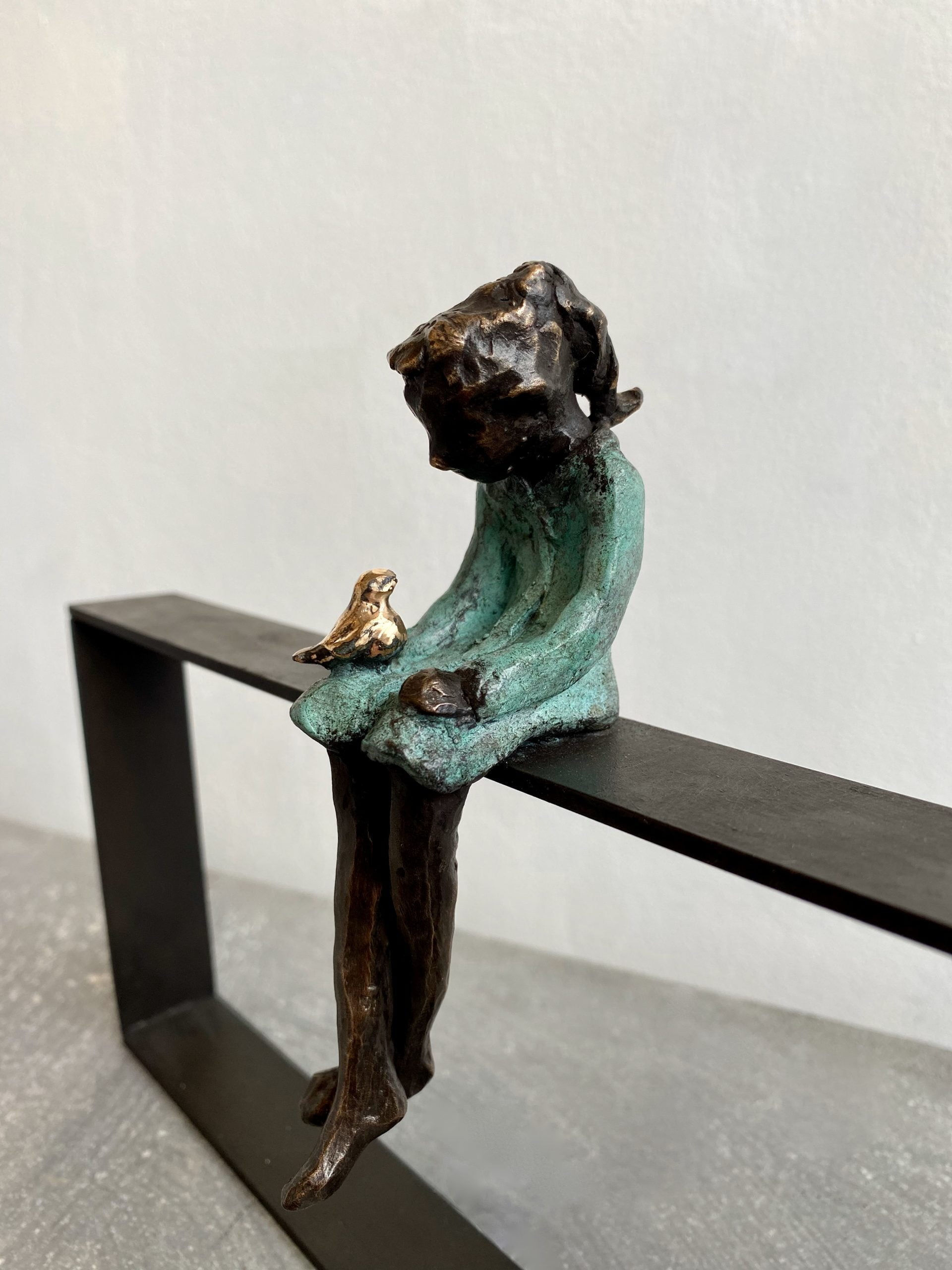 Bronzen beeldhouwwerk 'Mereltje op hekwerk ' door Cher Mattijssen: meisje met mereltje op schoot, op JolienVerhaegen.nl