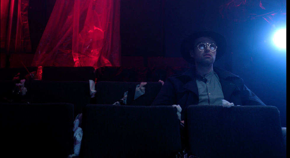 a man wearing glasses and a hat sits in a dark room