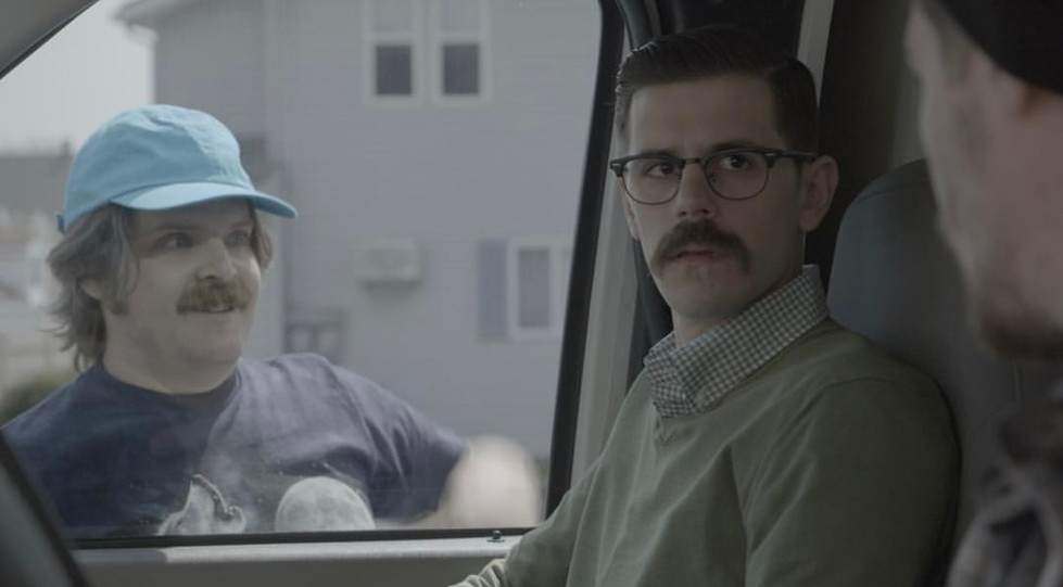 a man with glasses and a mustache is sitting in a car