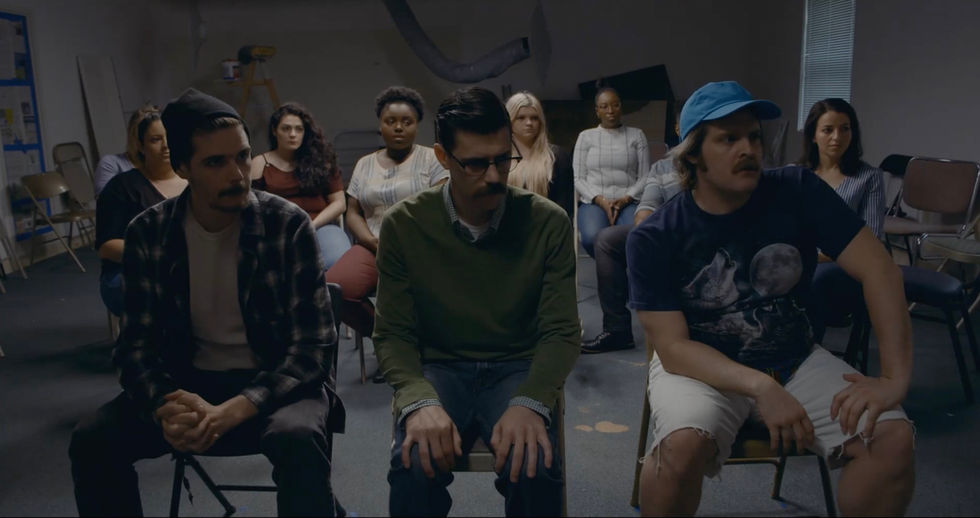 a group of people sitting in chairs with one man wearing glasses