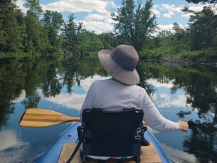 view of a woman from the back in a kayak looking at nature from the river