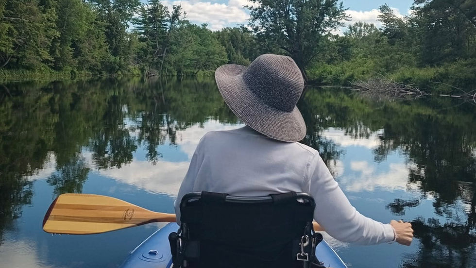 view of a woman from the back in a kayak looking at nature from the river