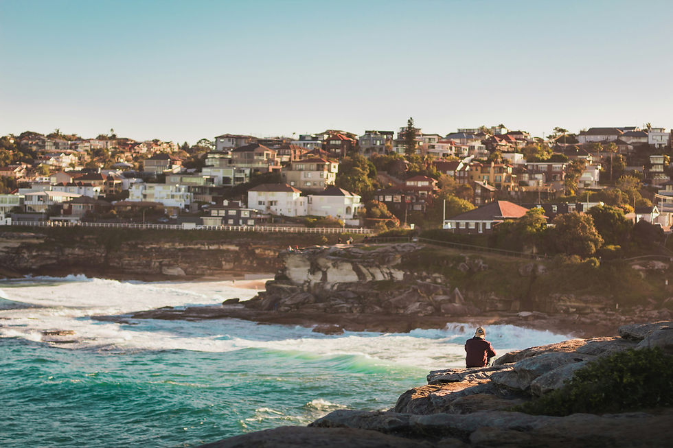 Person sitting on coastal rocks overlooking a turquoise bay